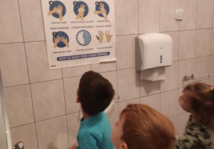 Chłopcy omawiają instrukcję prawidłowego mycia rąk.